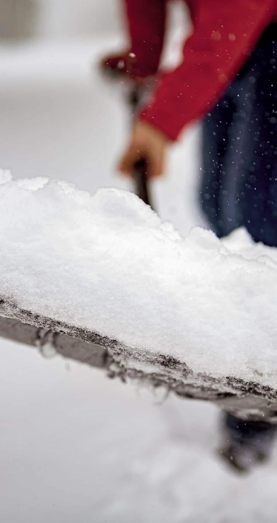 Closeup shot of snow on a snow shovel with a blurred background